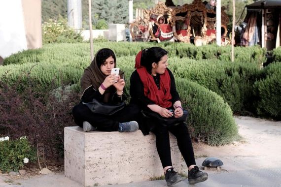 Iranian woman uses her mobile phone as she rests at a park in Tehran