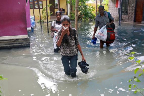 Residents carry their belongings as they evacuate their house after flooding caused by Cyclone Ockhi in the coastal village of Chellanam